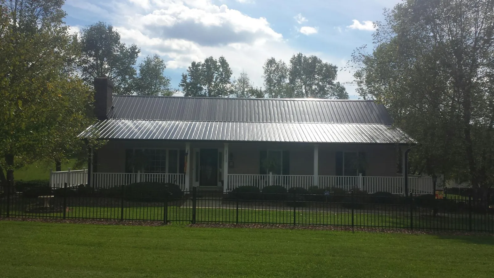 Gray metal roof on a brick ranch with a full width front porch — Gutter Guard Installation work by our crew in Bates City