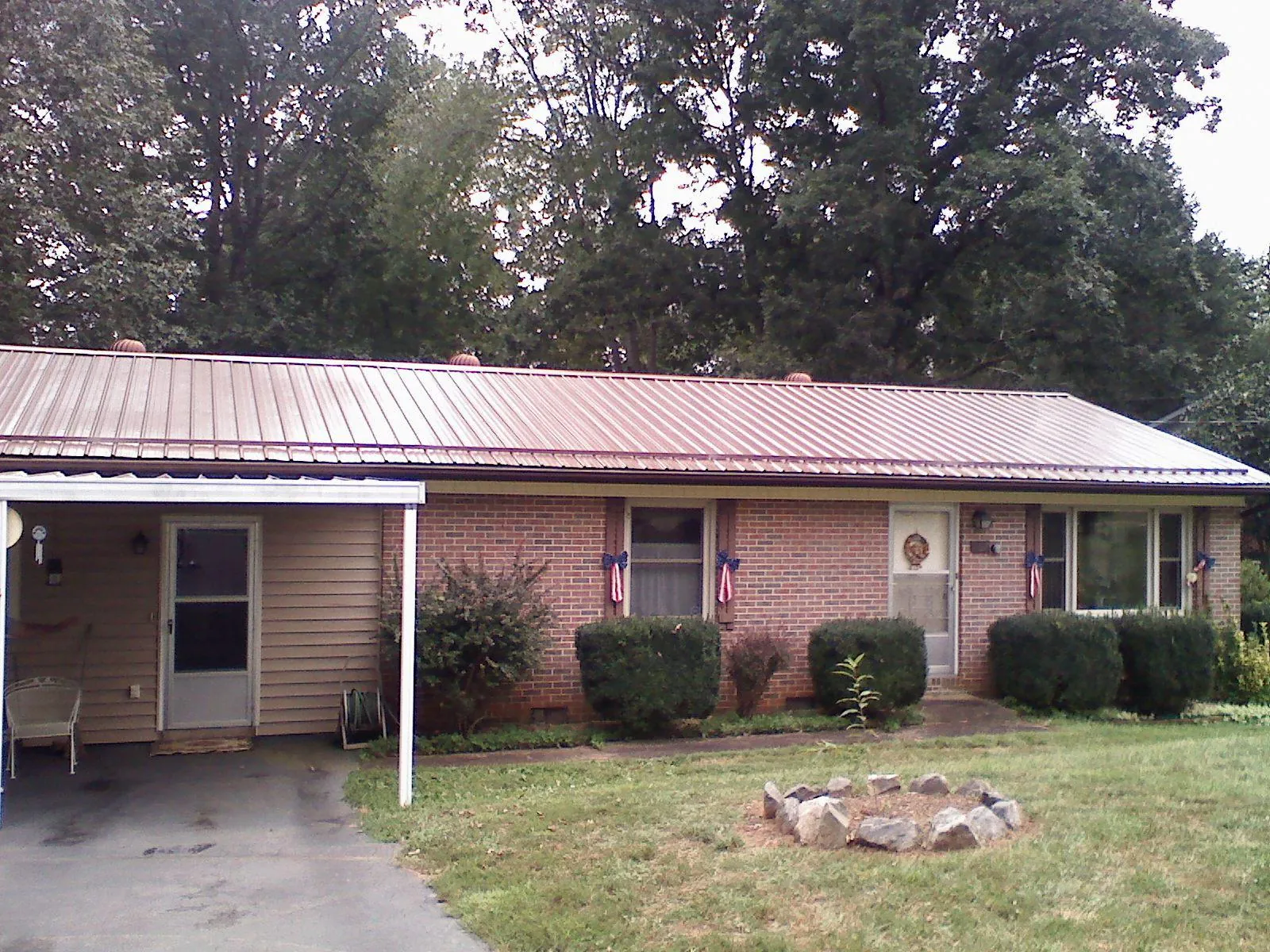 Bronze metal roof and carport on a brick ranch home — Roof Repair work by our crew in Bates City