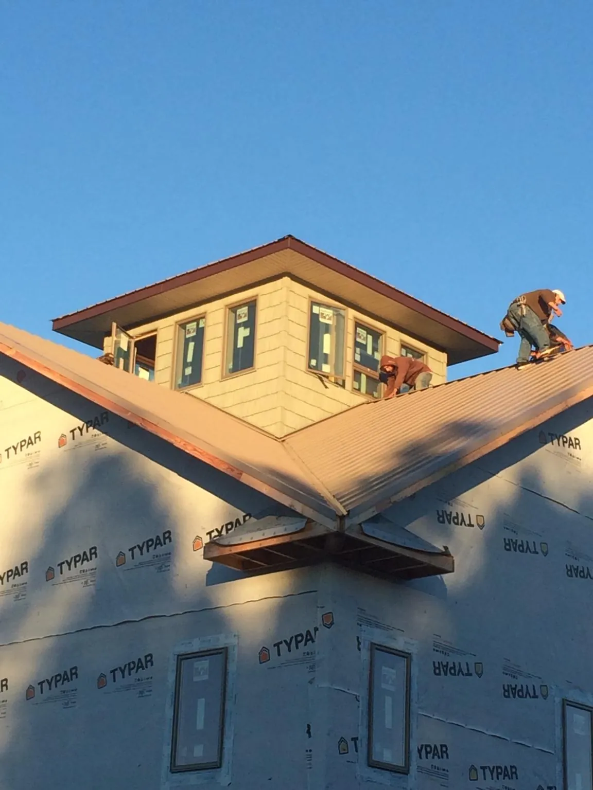 Roofers working around a rooftop cupola on a new metal roof at sunset — Roof Waterproofing in Bates City by Roofing Brothers